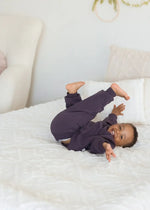 A child lying on a neutral blanket in a GOTS certified organic cotton jogger set.