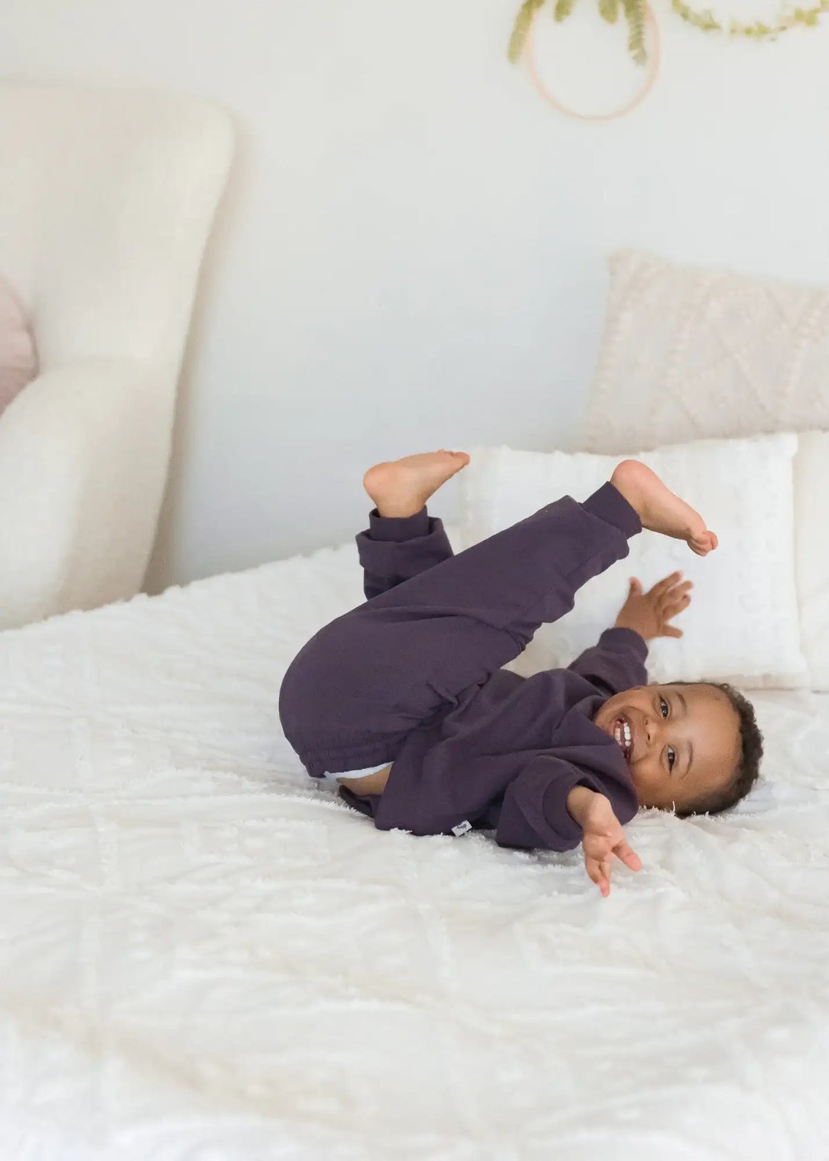 A child lying on a neutral blanket in a GOTS certified organic cotton jogger set.