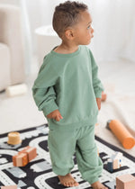 A toddler standing and looking away from the camera while wearing an organic cotton jogger set.