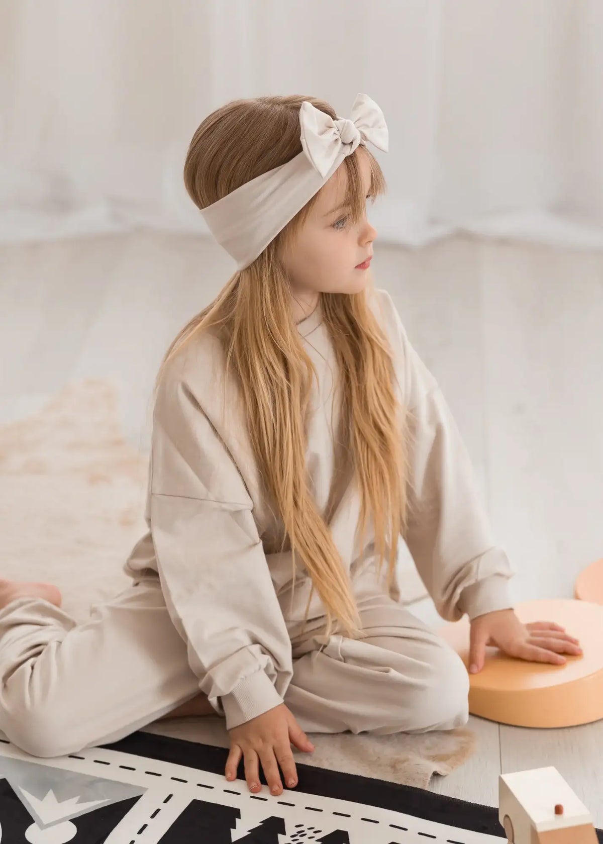 A child sitting on the floor wearing an organic cotton jogger set from Milana Label.