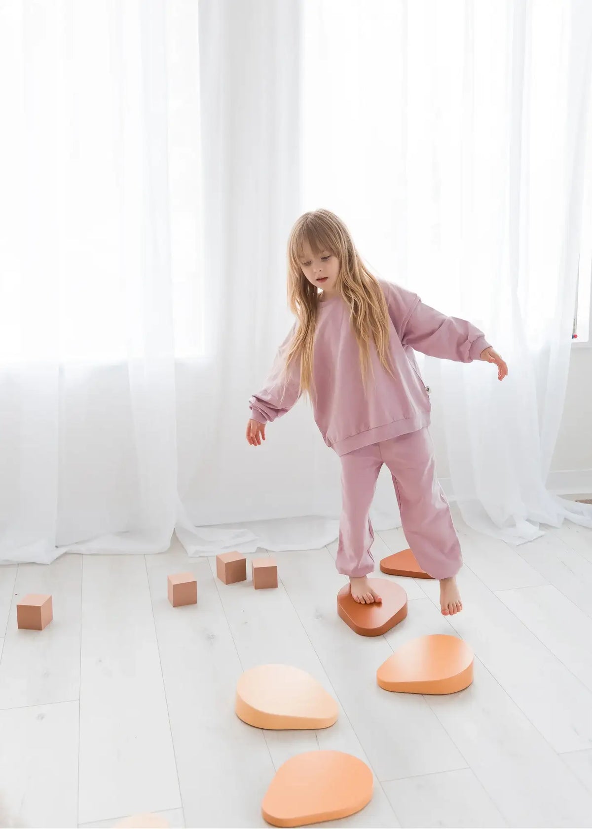 A young girl balancing on steppers wearing a matching two-piece set in the colour Pale Orchid.
