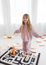 A child standing on a playmate wearing an organic cotton jogger set by Milana Label.